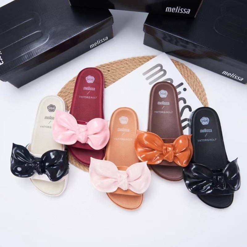 melissa bow-tie flip-flops with beach shoes on top of them